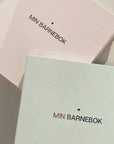 Min Barnebok – en vakker minnebok som bevarer de viktigste øyeblikkene fra småbarnsårene og frem til skolestart (1-6 år). Perfekt for å dokumentere milepæler som første sykkeltur, mistet tann, barnehagetid, bursdager, gullkorn, ferieminner og fritidsaktiviteter. Oppfølgeren til Min Babybok, designet for å skape en helhetlig samling av barndomsminner. Ideell som dåpsgave, bursdagsgave eller gave til nybakte foreldre. Legg til initialer for en personlig touch! En stilren, detaljrik og tidløs barne minnebok!