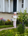 Barn med lys rosa barnelue i kasjmir i hagen