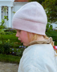 Barn med lys rosa barnelue i kasjmir sett fra siden